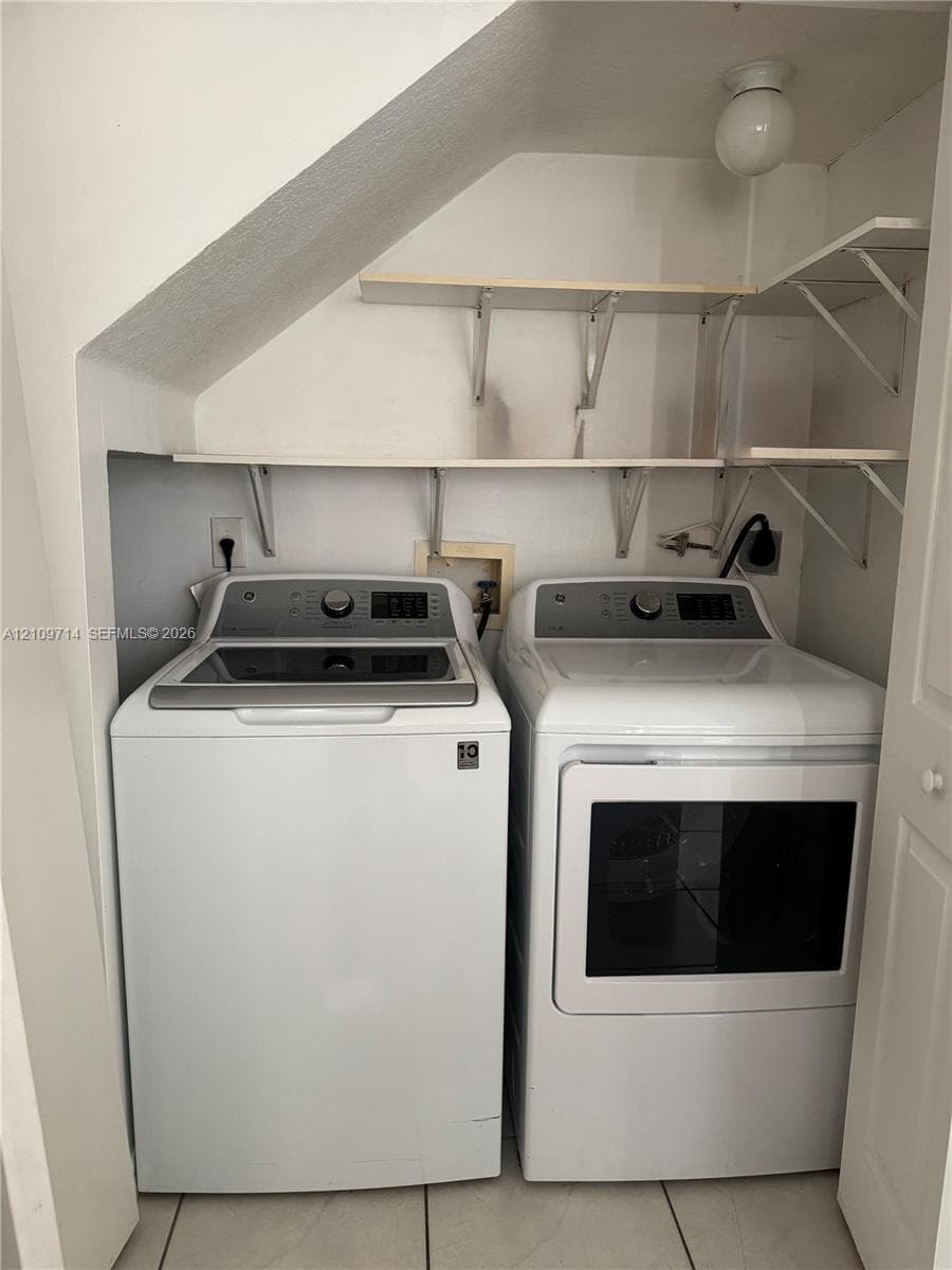 Laundry area featuring built-in shelving, tile flooring, and overhead lighting
