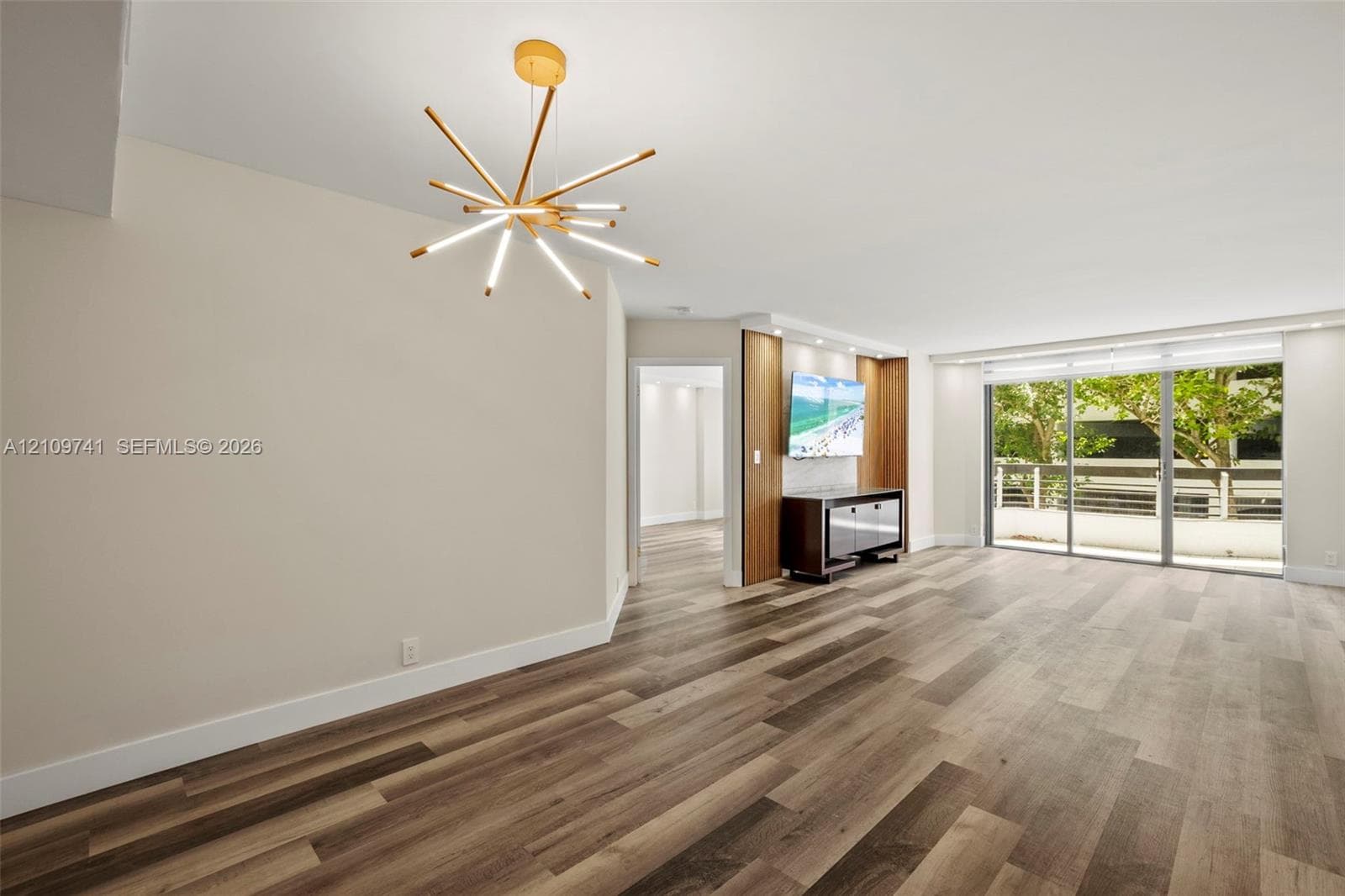 Wood-finish flooring, multi-arm contemporary pendant light, custom built-in cabinetry with integrated accent lighting, and expansive sliding glass doors