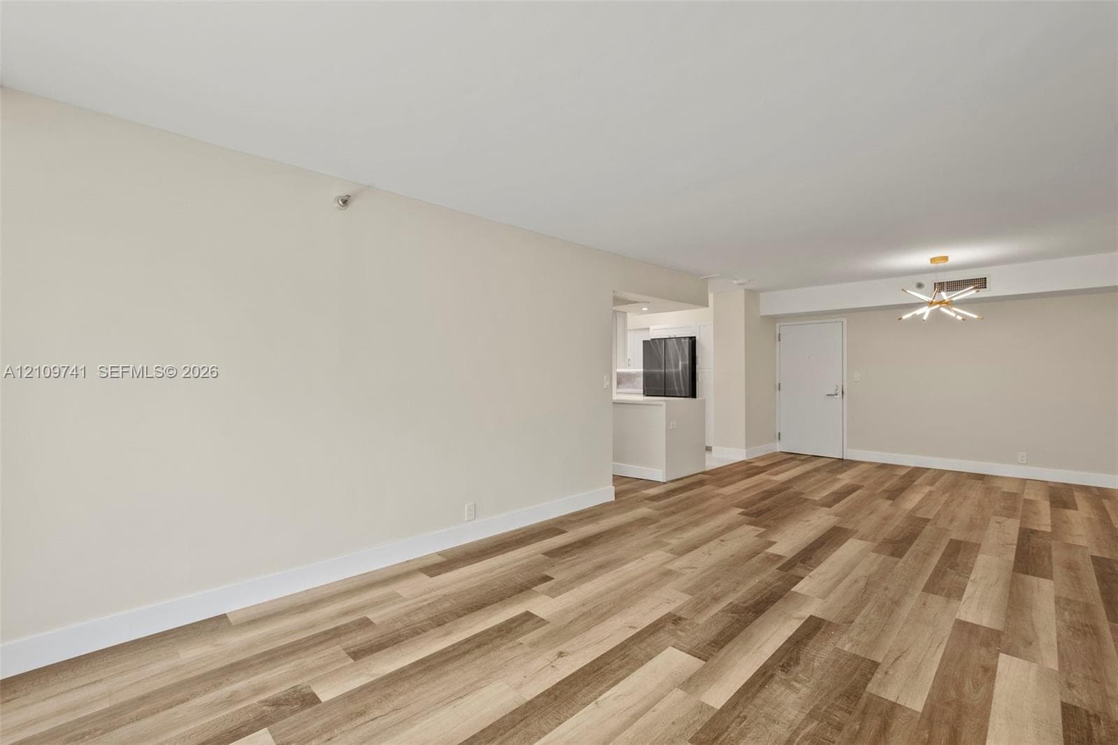 Open-concept interior featuring wood-finish plank flooring, neutral wall tones, and a modern sputnik-style chandelier