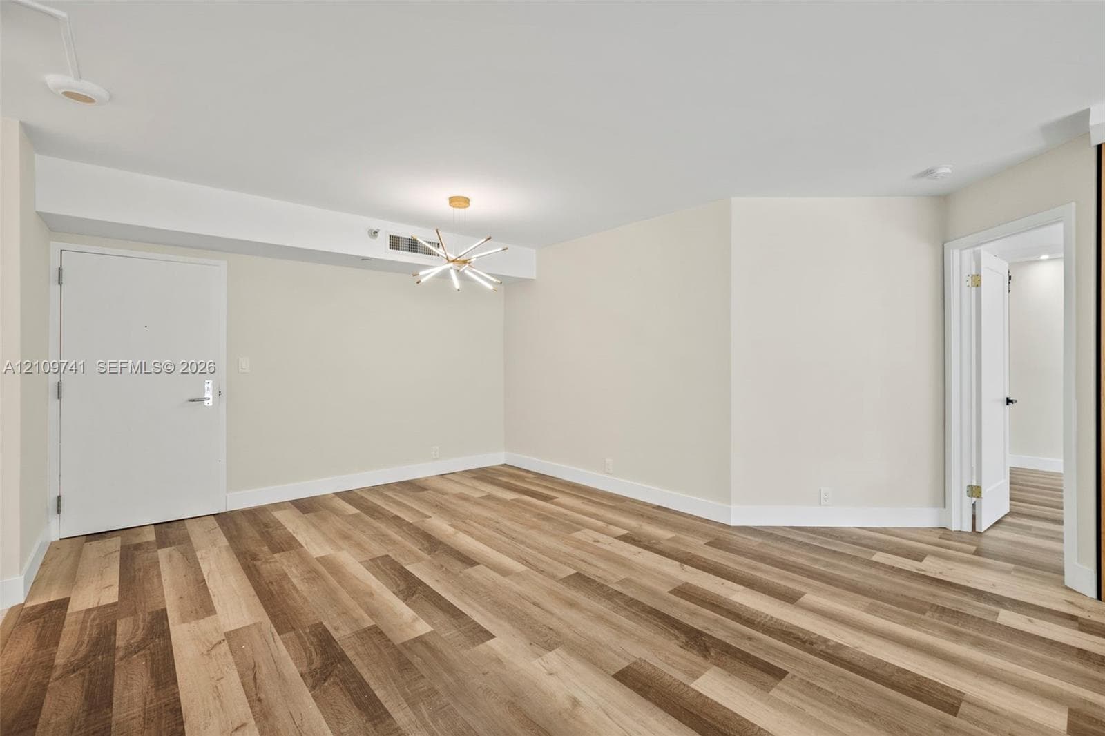 Interior space featuring wood-finish flooring, a modern multi-arm starburst chandelier, and smooth-finish walls