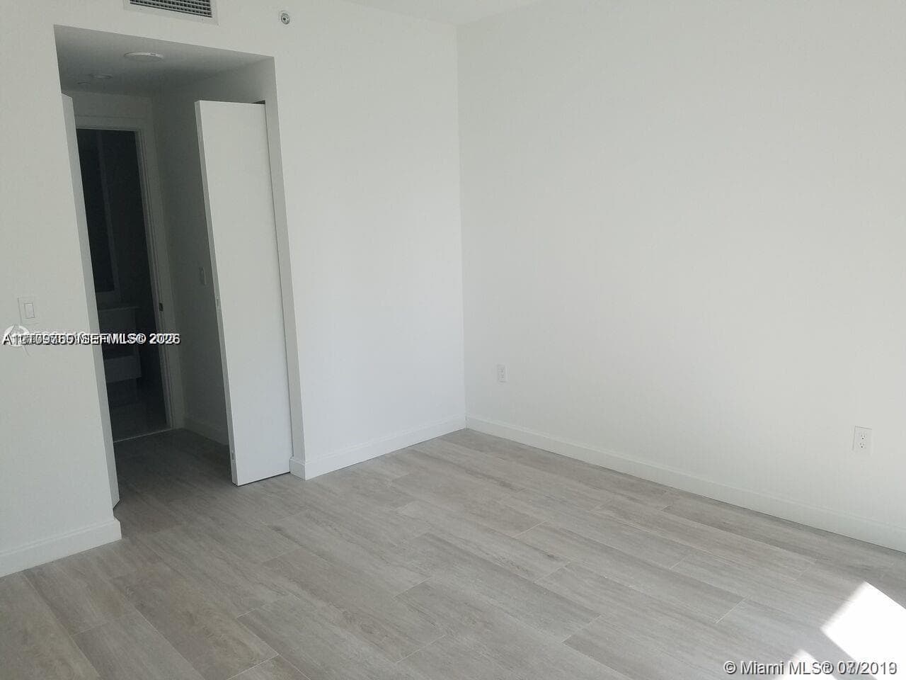 Neutral interior featuring wood-finish flooring, white walls, and a recessed ceiling lighting fixture