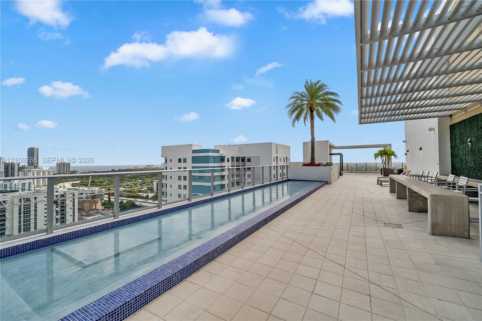 Rooftop terrace featuring an infinity-edge pool, tiled flooring, metal louvered pergola, and glass railings