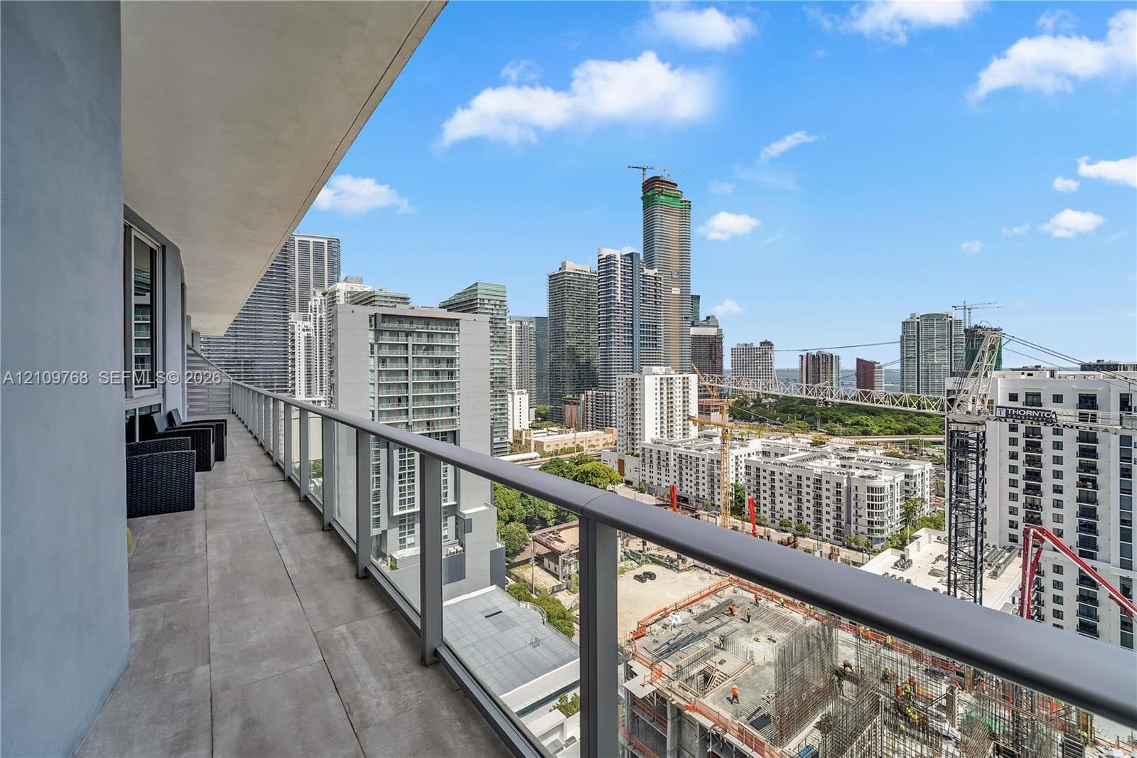 Covered balcony featuring large-format tile flooring and a glass-panel railing with metal frame