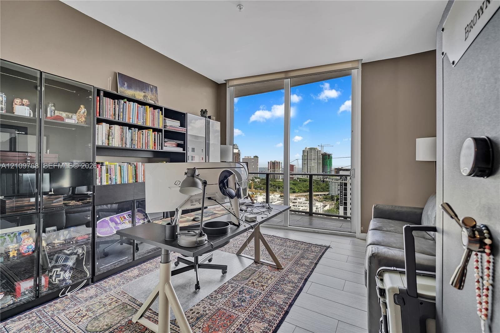 Floor-to-ceiling glass door, built-in floor-to-ceiling shelving, light-toned tile flooring, and a private balcony