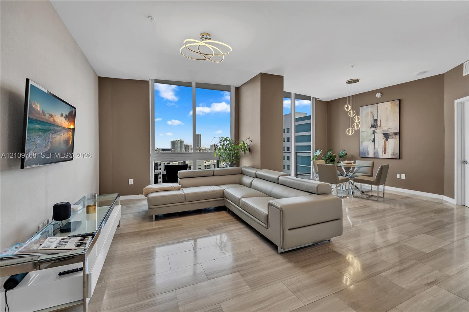Open-concept interior featuring floor-to-ceiling windows, polished stone-finish flooring, architectural LED light fixtures, and multi-directional overhead pendant lighting