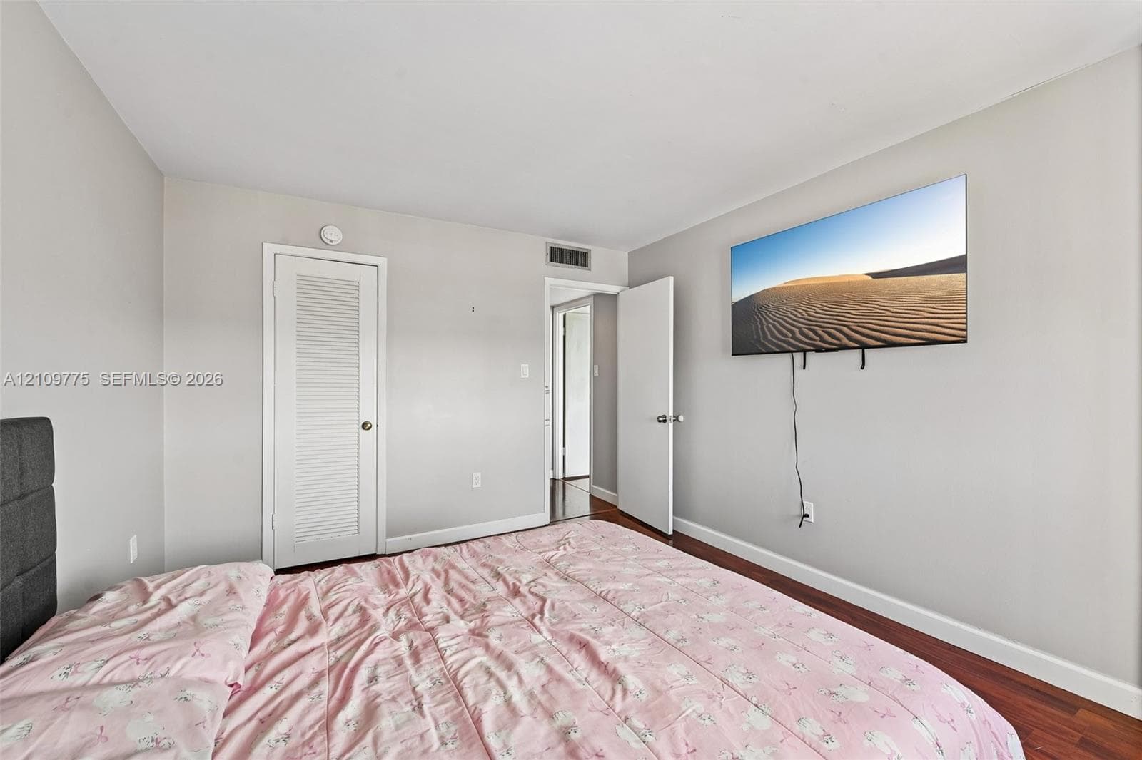 Room featuring wood-finish flooring, a louvered-panel door, and smooth-finish walls