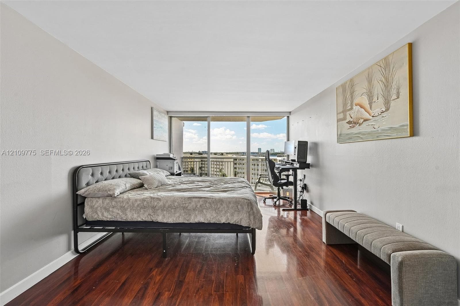 Wood-finish flooring, neutral wall tones, and floor-to-ceiling glass sliding doors opening to an exterior balcony