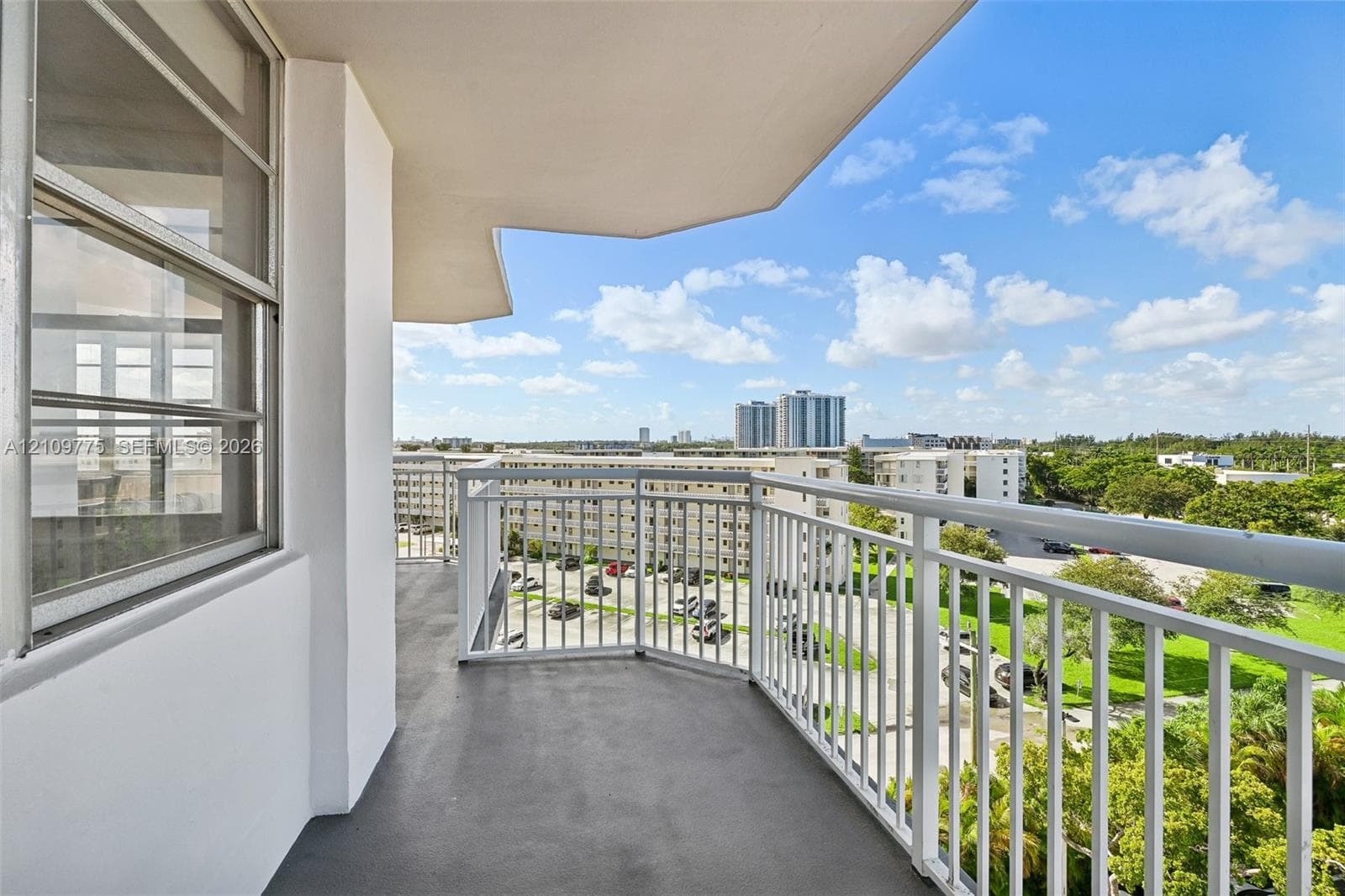 Covered balcony featuring white metal railings, concrete flooring, and sliding glass entry doors