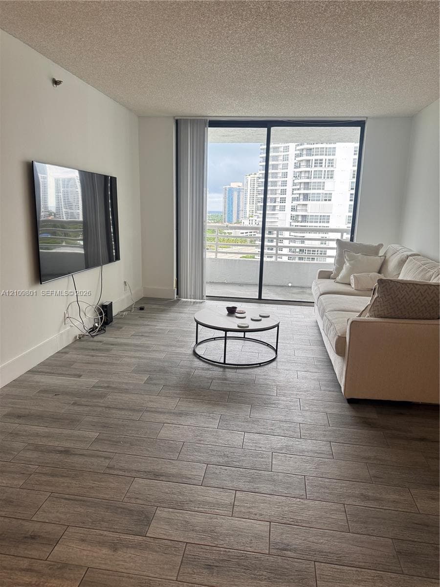 Living area featuring wood-finish flooring and large sliding glass doors opening to a private balcony