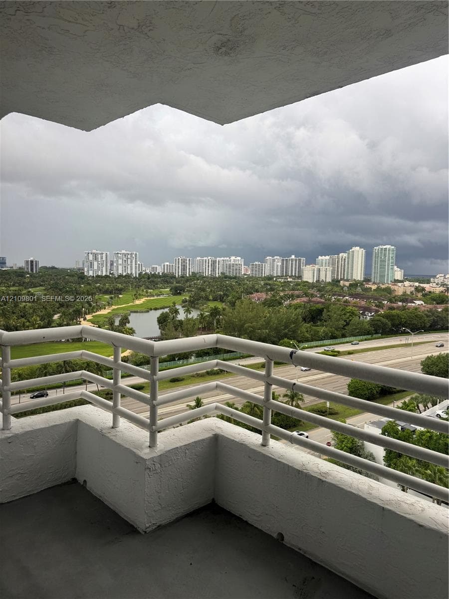Covered balcony featuring white metal railings and concrete flooring