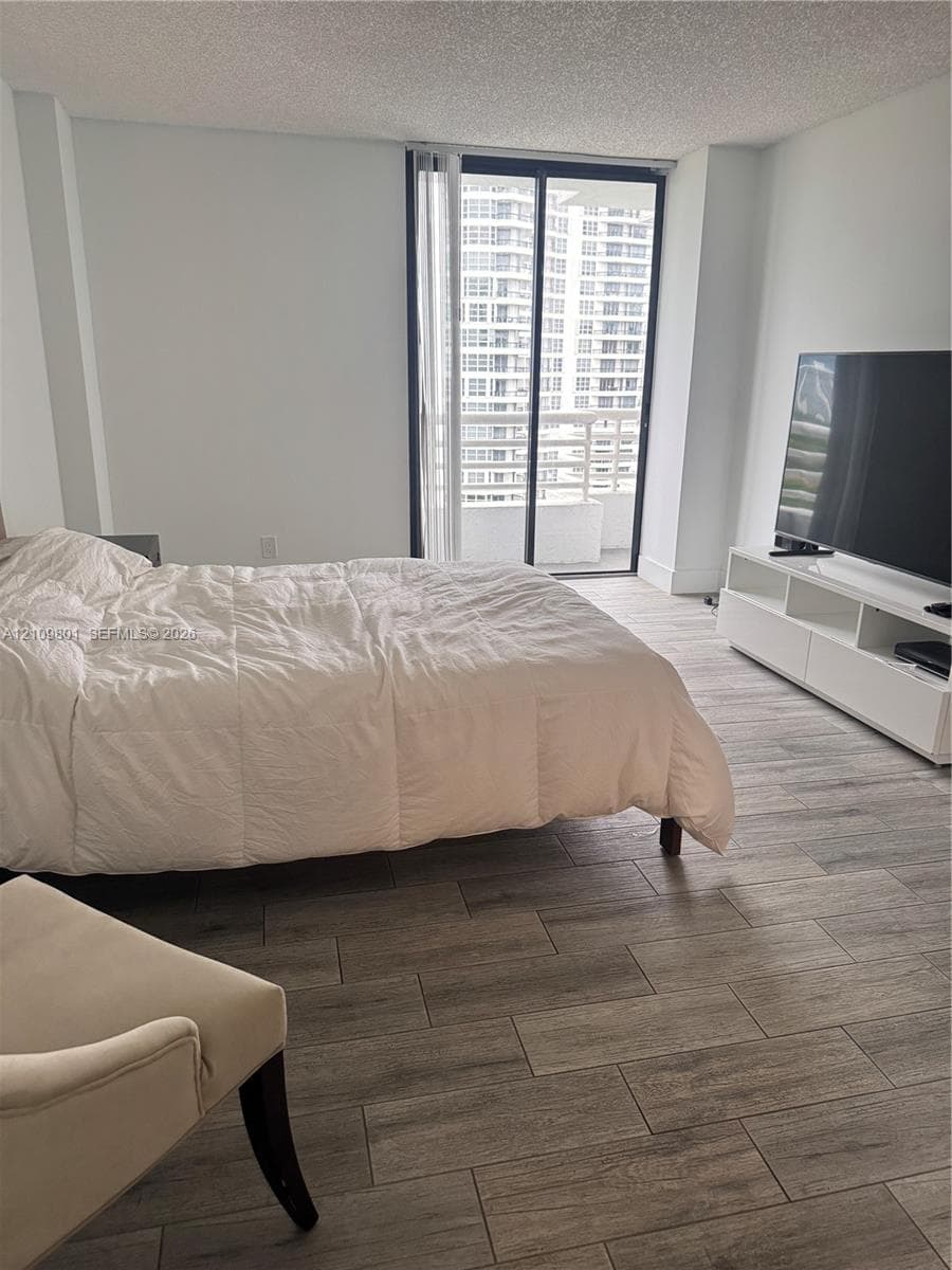 Wood-finish tile flooring, sliding glass balcony doors, and neutral wall tones