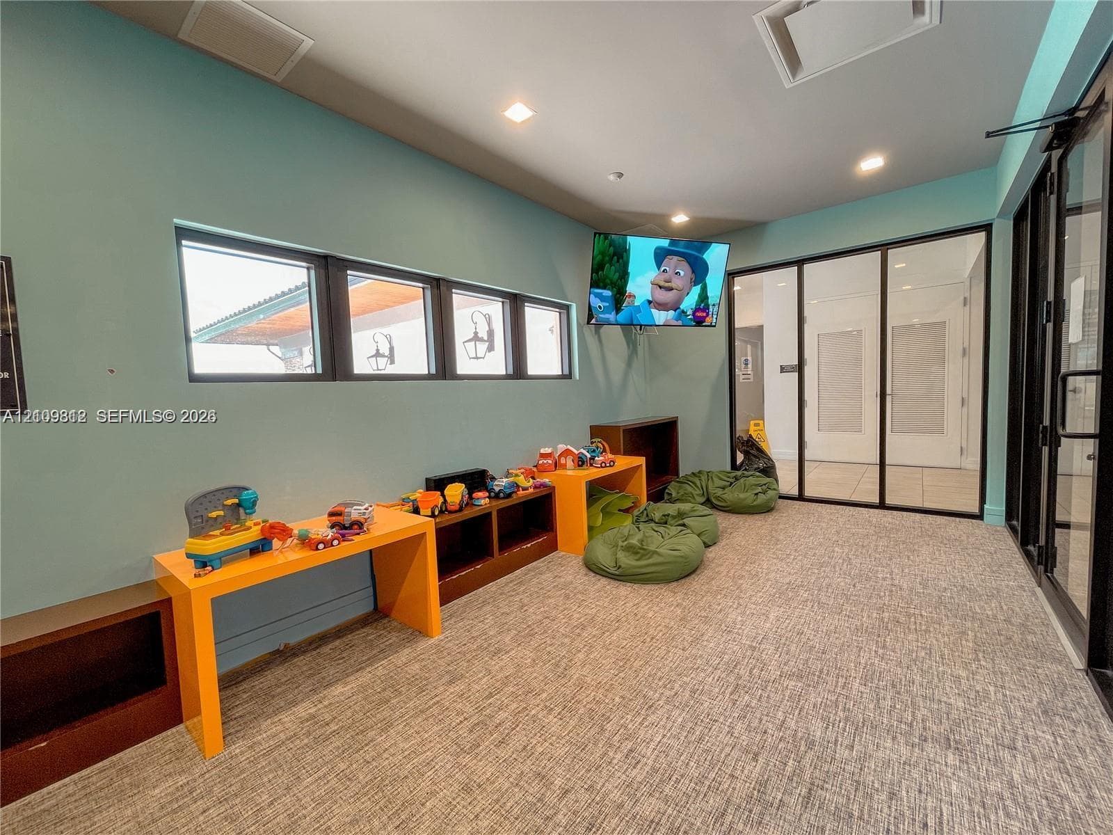 Multi-purpose room featuring built-in cabinetry, recessed lighting, expansive windows with dark frames, and floor-to-ceiling glass partitions