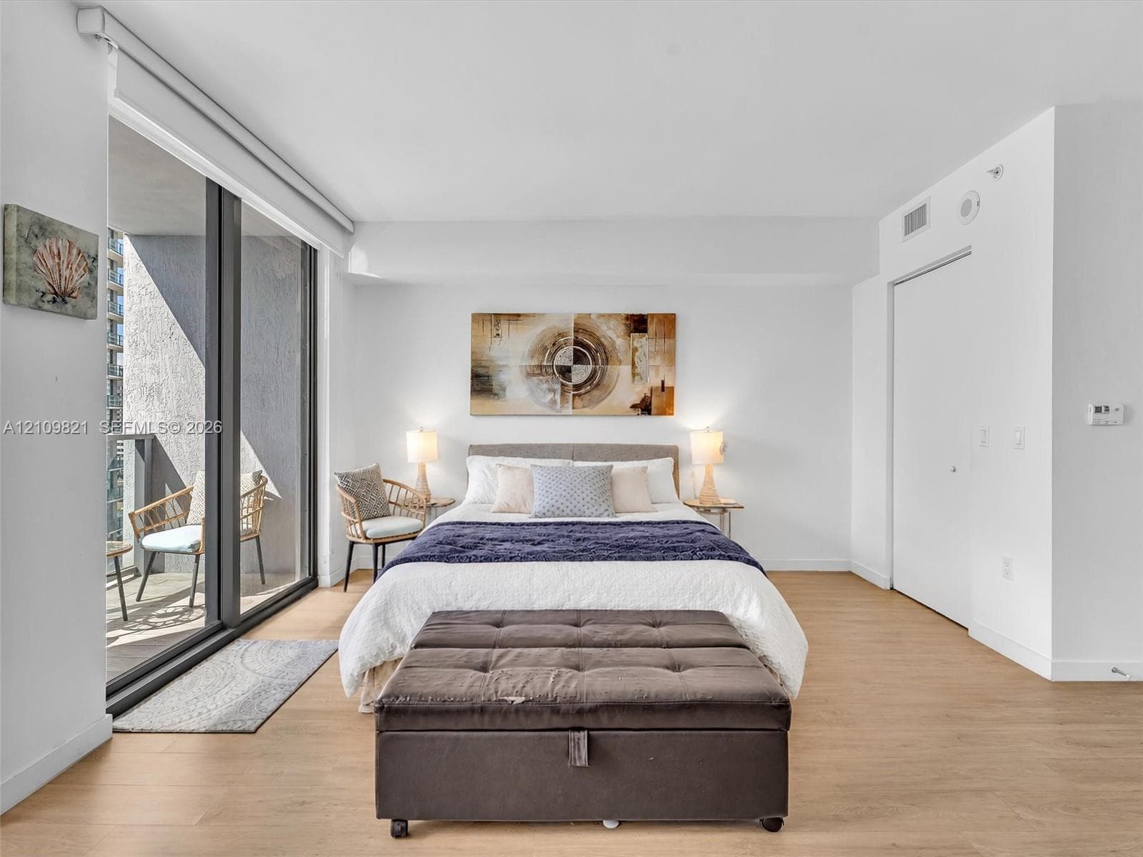 Floor-to-ceiling sliding glass door, private balcony, and light-tone wood-finish flooring