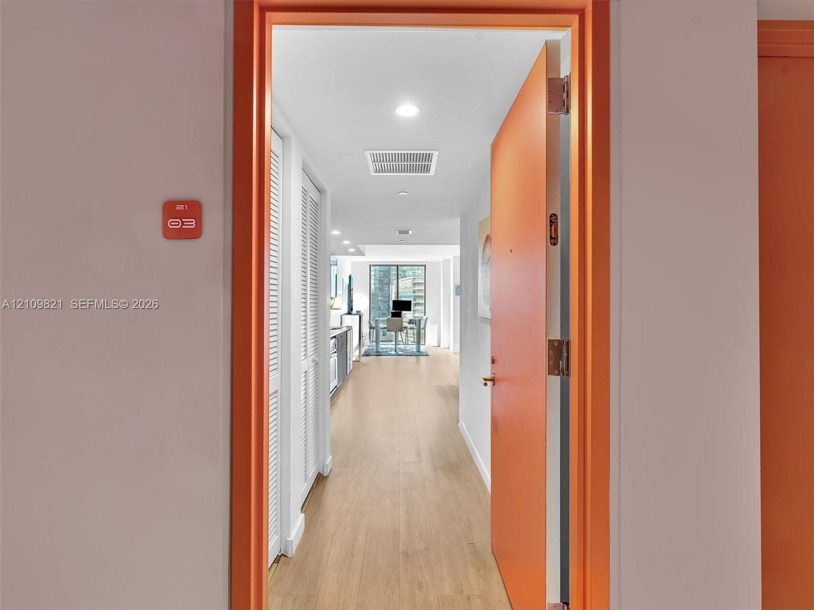 Entryway featuring wood-finish flooring, white louvered closet doors, and recessed ceiling lighting