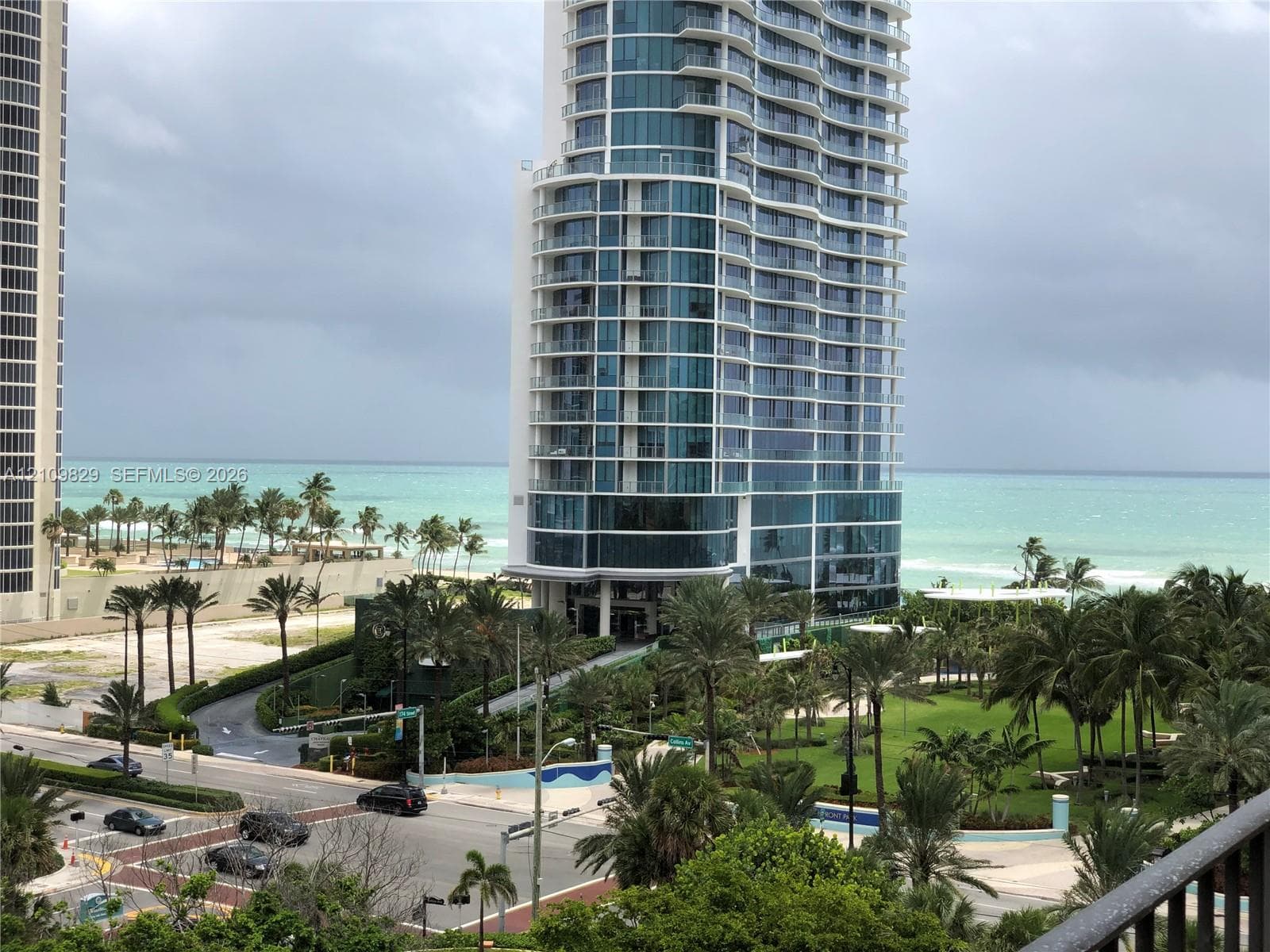 High-rise residential tower featuring a glass-curtain facade, wraparound balconies, and coastal proximity