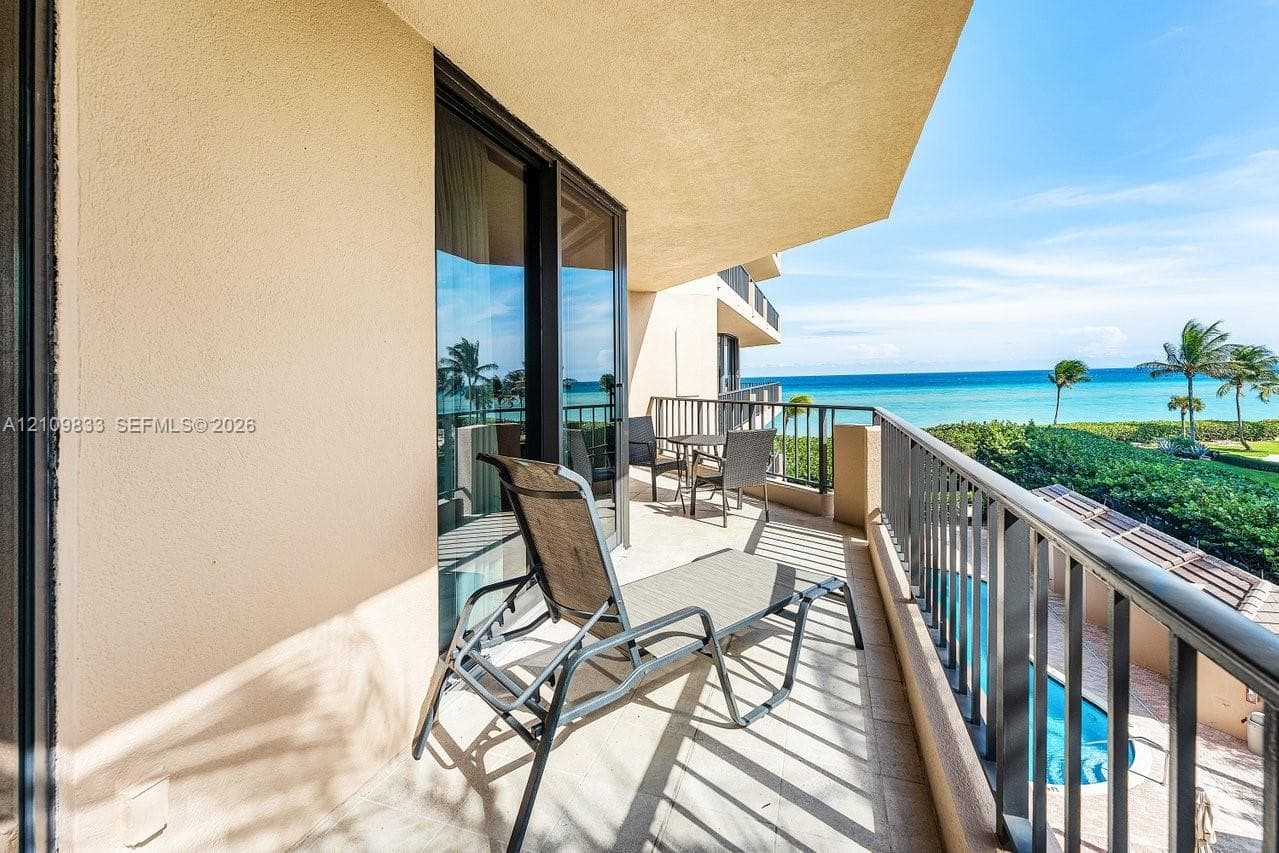 Covered balcony featuring tile flooring, metal railings, and sliding glass door entry
