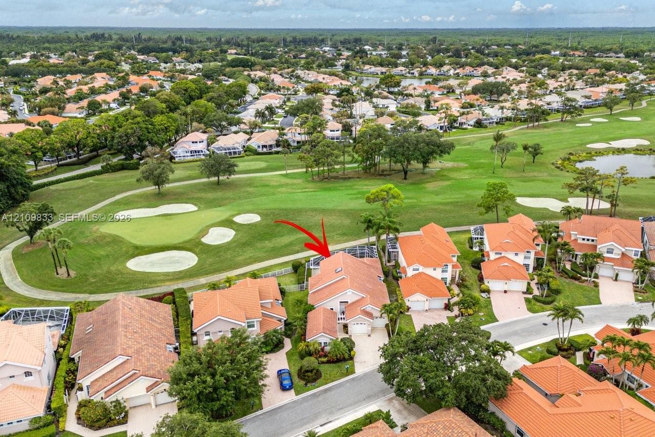 Aerial perspective of a multi-gabled residence featuring a concrete tile roof, skylight, enclosed lanai, and frontage along a golf course