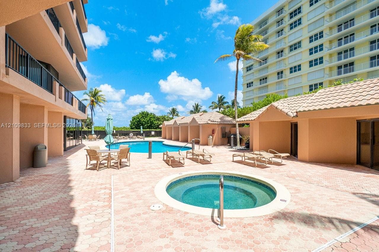 Community pool area featuring an in-ground spa, paver deck, and covered poolside cabanas