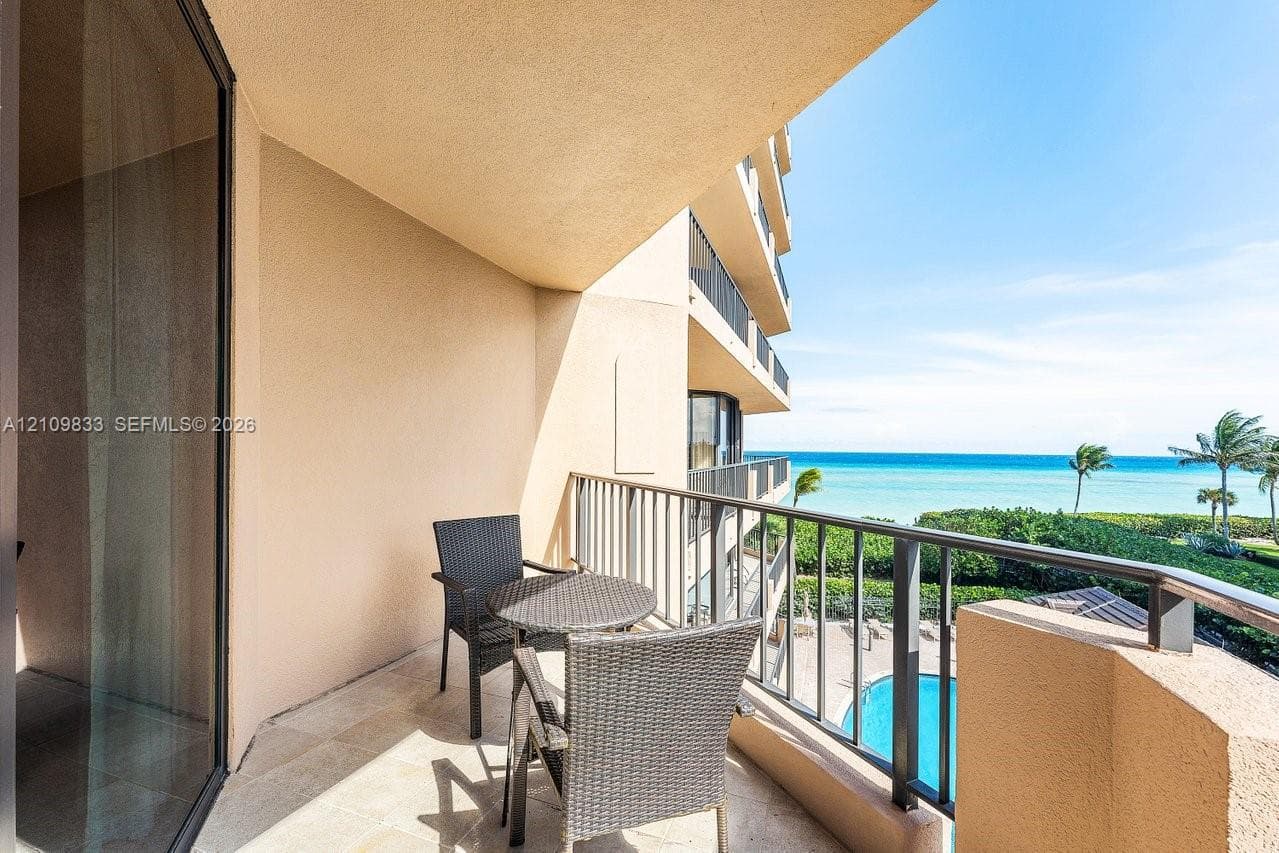 Covered balcony featuring stone-finish flooring, metal railing, and ocean scenery