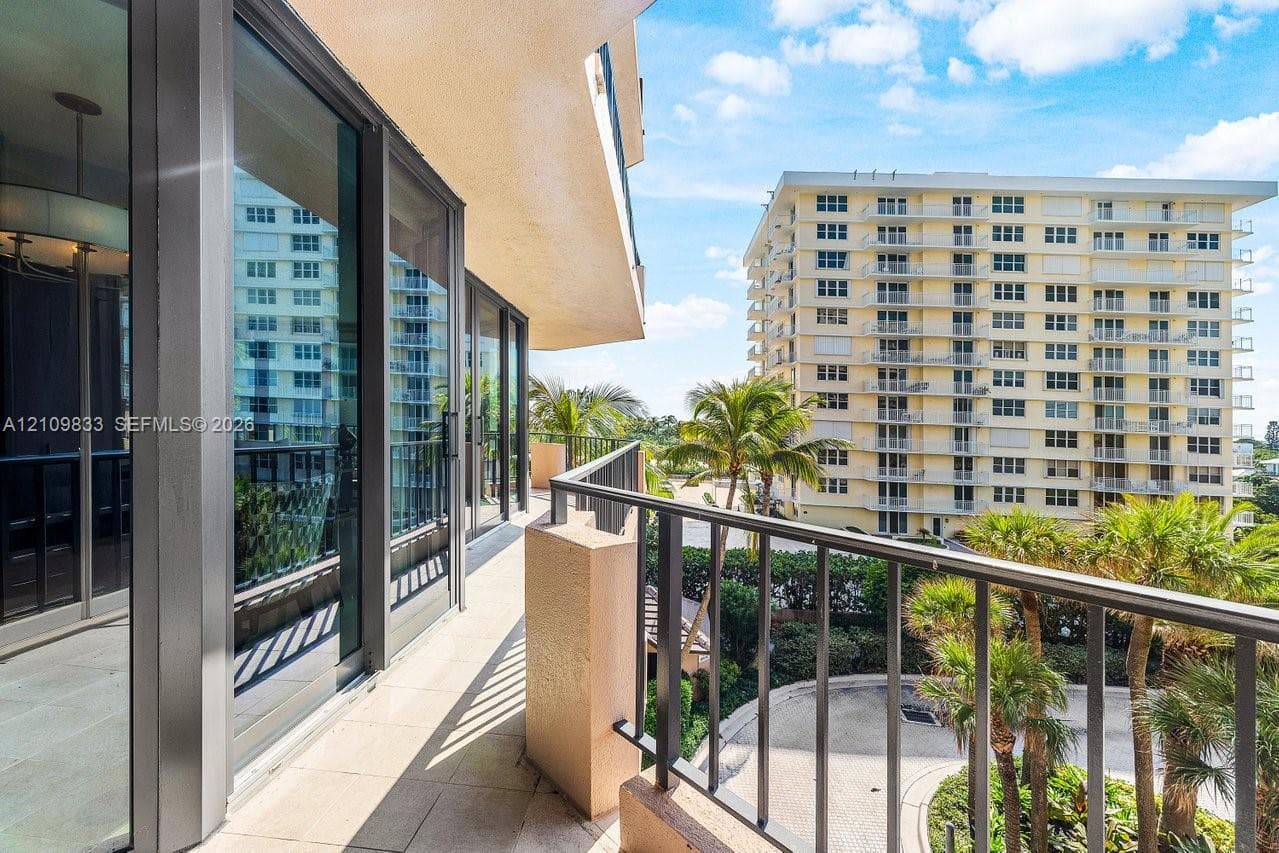 Covered balcony featuring expansive glass sliding doors, stone-finish flooring, and a metal railing