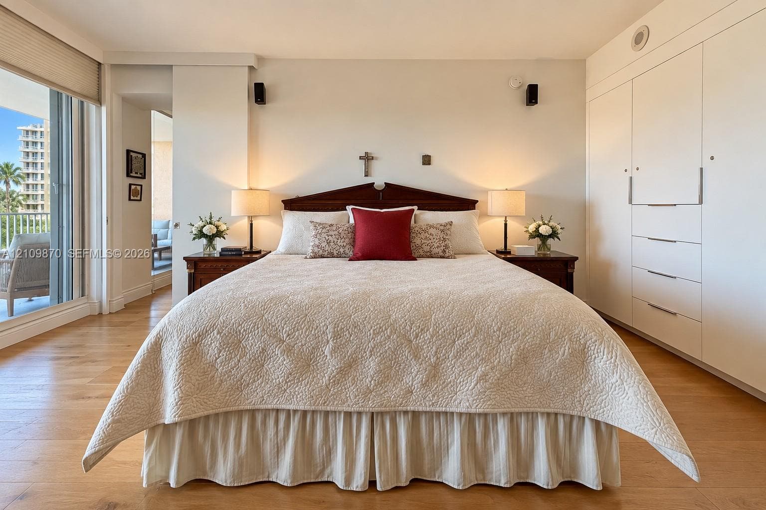 Wood-finish flooring, floor-to-ceiling built-in white cabinetry, and sliding glass doors leading to an exterior balcony