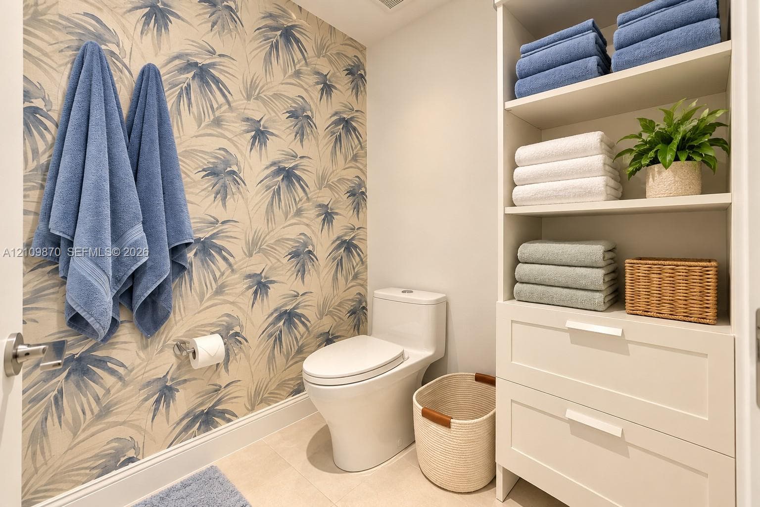 Botanical-patterned wallpaper, dual-piece toilet, and built-in floor-to-ceiling cabinetry featuring open shelving and two storage drawers