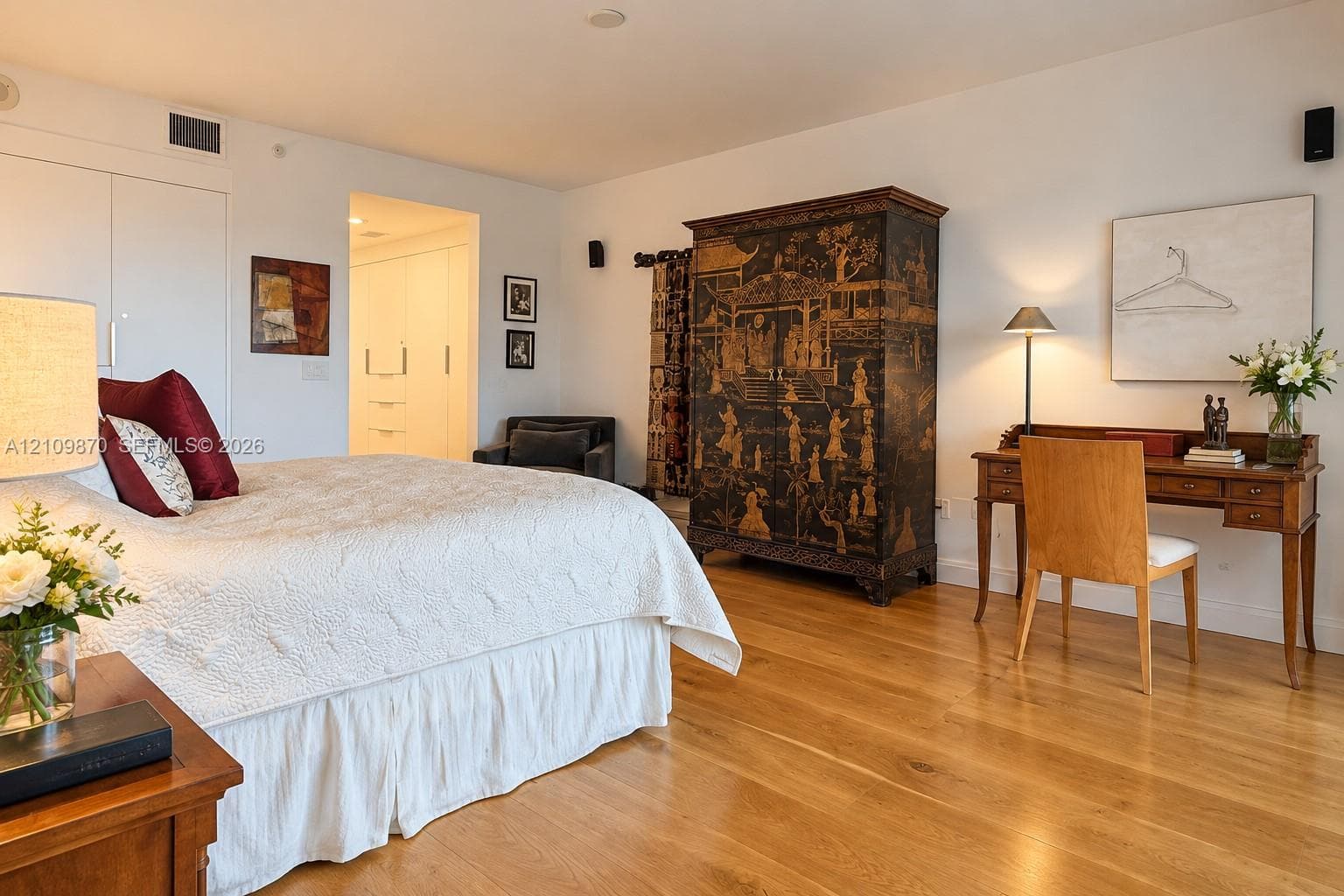 Room featuring wood-finish flooring, smooth-finish walls, and built-in closet cabinetry