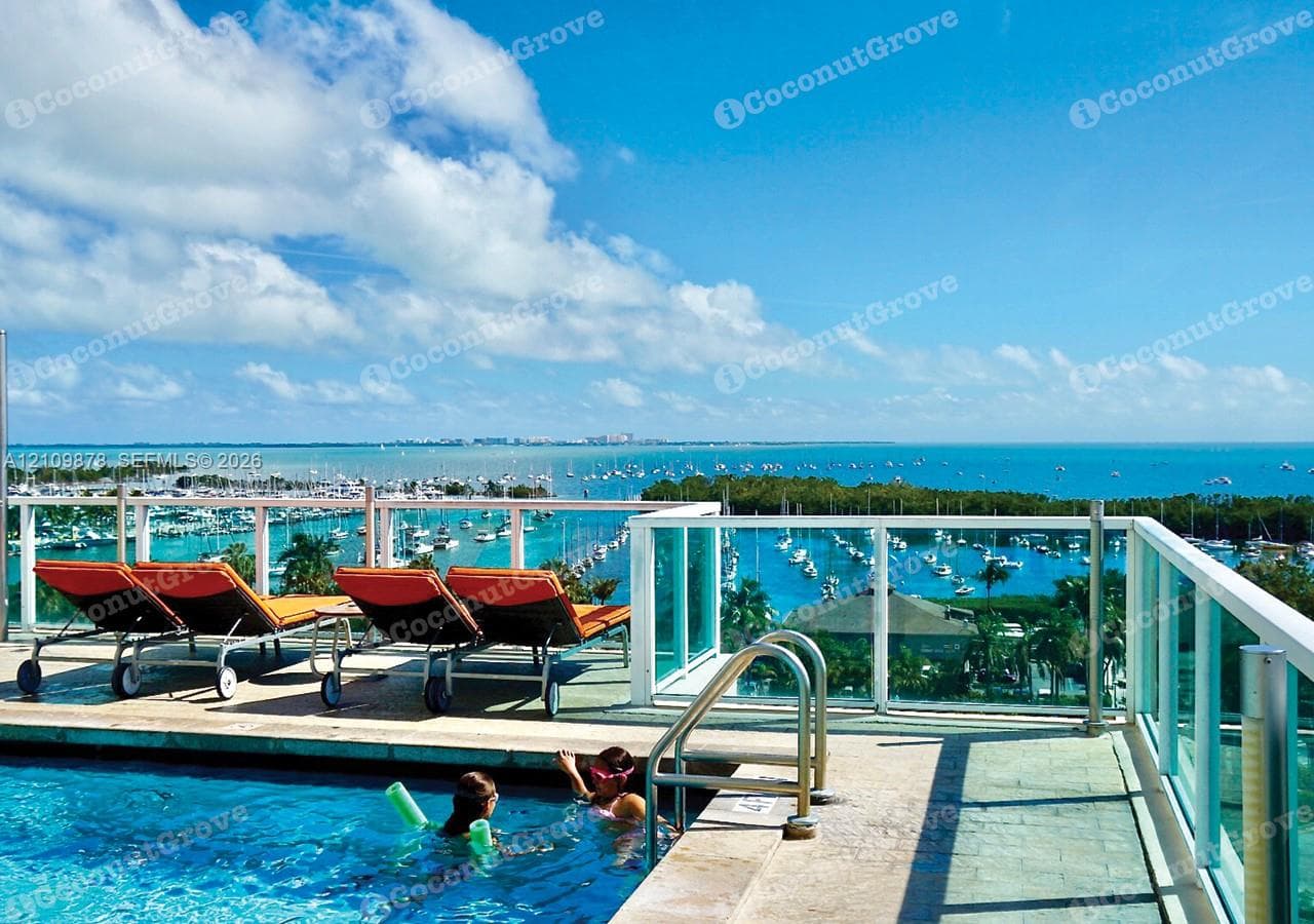 Rooftop swimming pool featuring a stone-tile deck and metal railings with glass panels