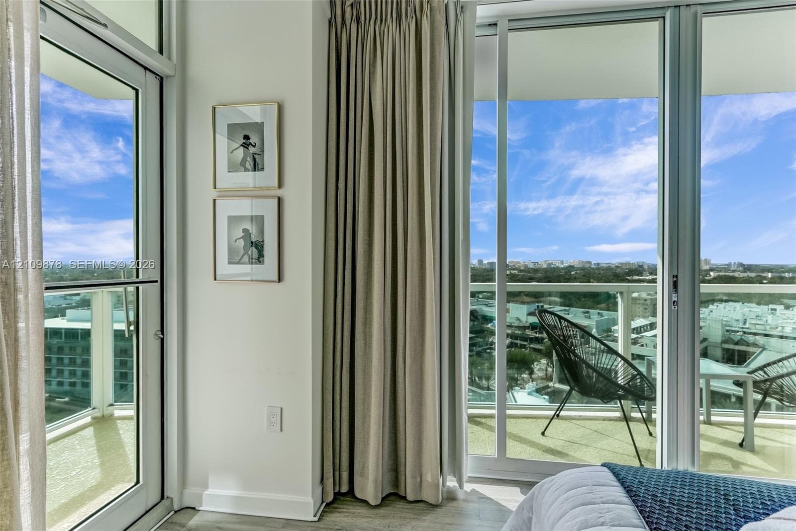 Floor-to-ceiling glass sliding doors, private balcony, and light-toned wood-finish flooring