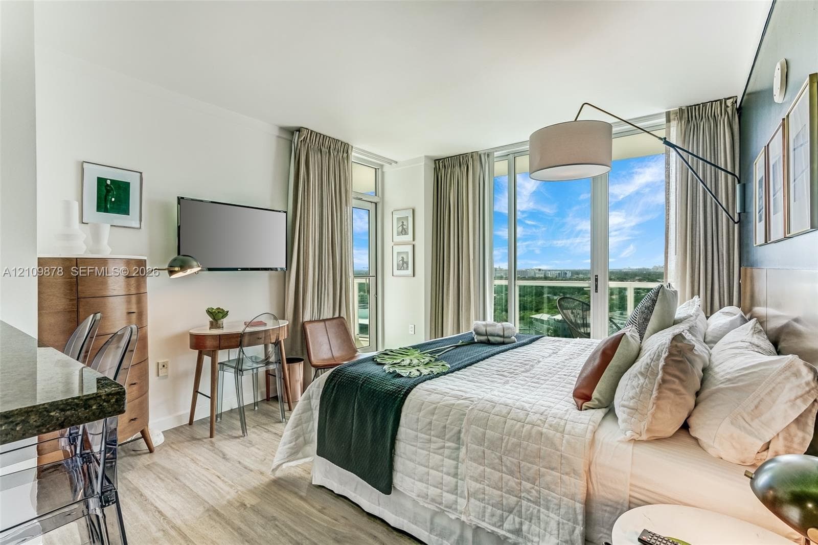 Floor-to-ceiling windows, wood-finish flooring, wall-mounted adjustable light fixture, and balcony access