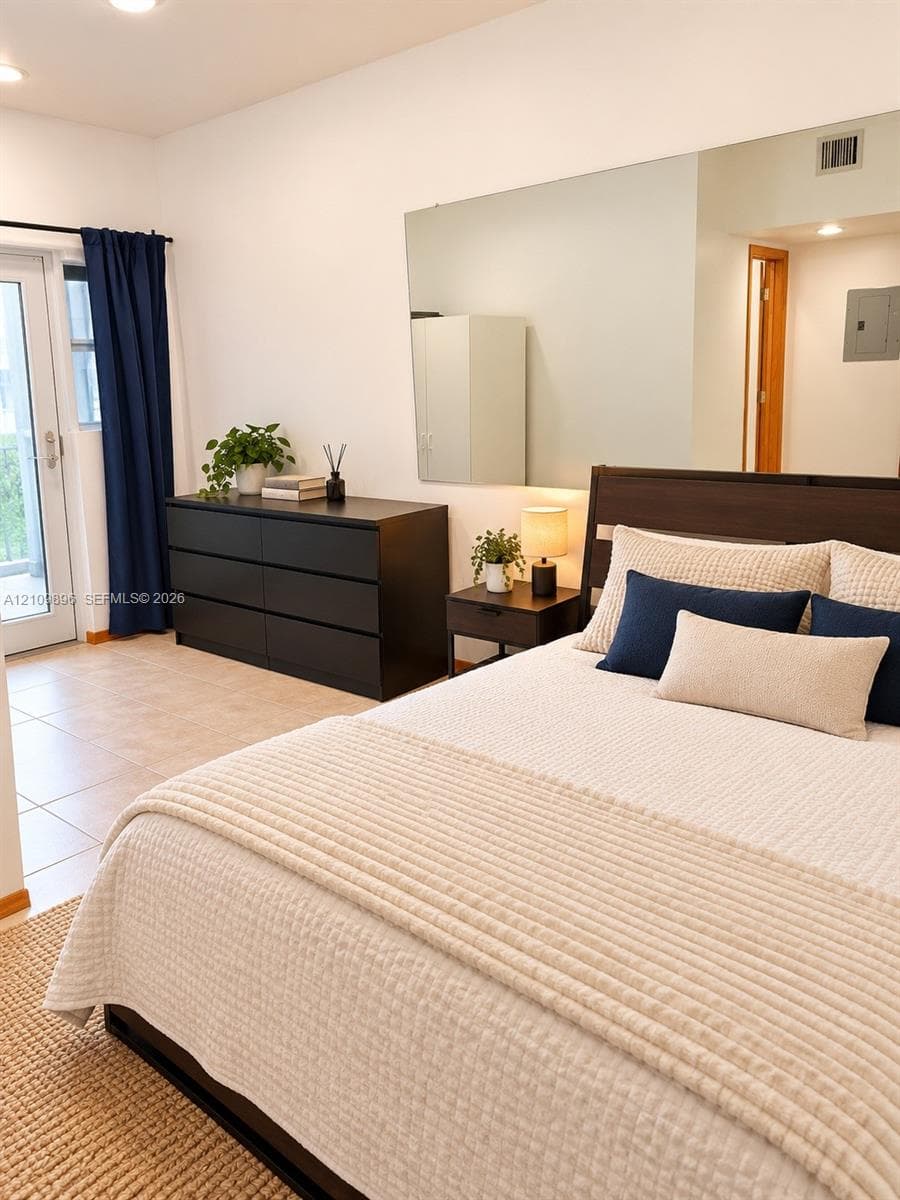 Ceramic tile flooring, wall-mounted mirror, and glass-paneled exterior door with natural light exposure