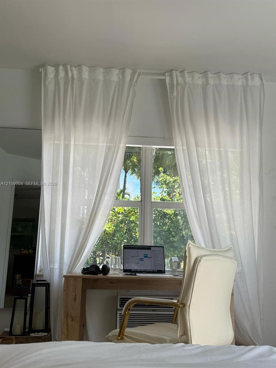 Multi-pane window featuring a window-mounted air conditioning unit and exterior tropical foliage