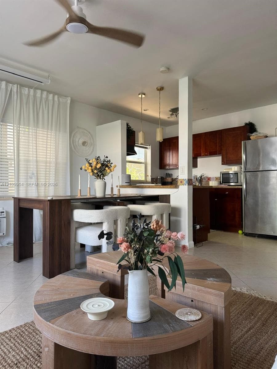 Interior space featuring tile flooring, a modern three-blade ceiling fan, recessed and pendant lighting, and kitchen cabinetry with stainless steel appliances