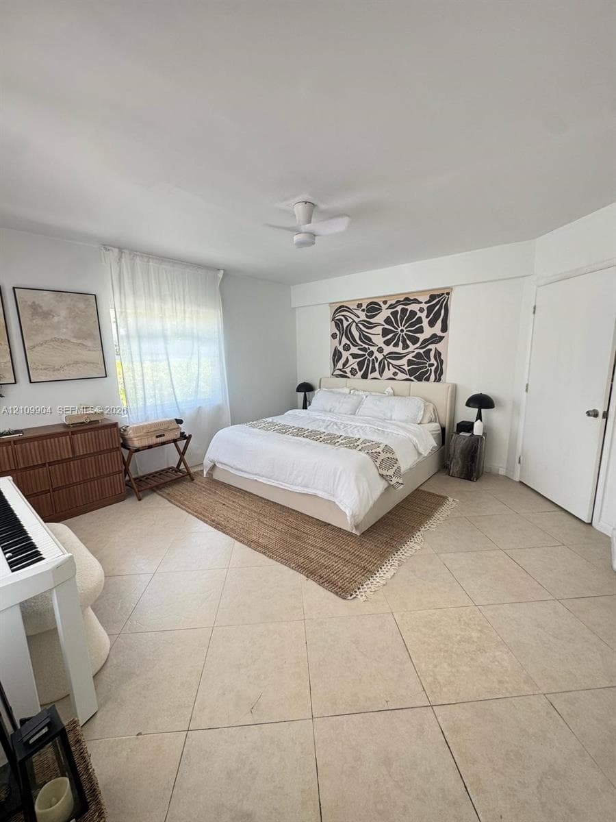 Neutral-toned tile flooring, white wall finishes, and a ceiling-mounted fan fixture