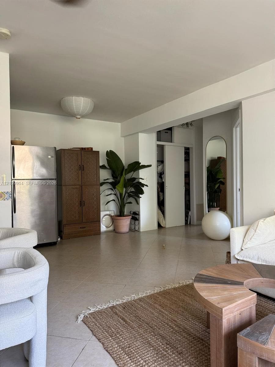 Neutral tile flooring, stainless steel refrigerator, and built-in closet with sliding doors
