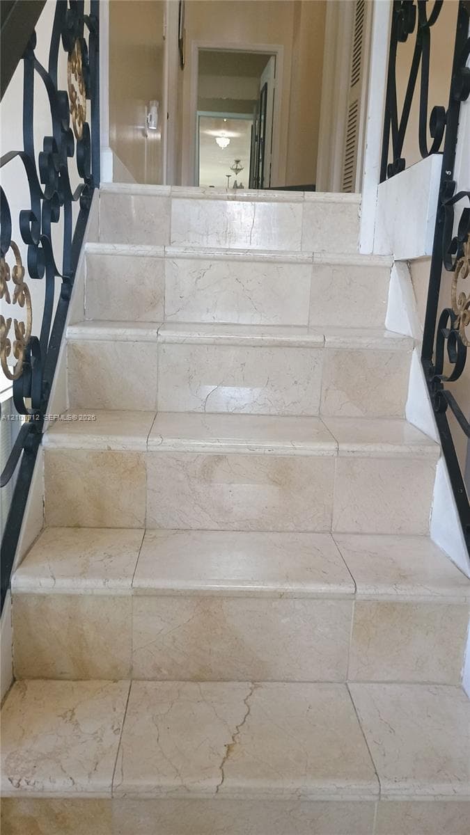 Staircase featuring stone-finish treads and risers with ornate black metal railings