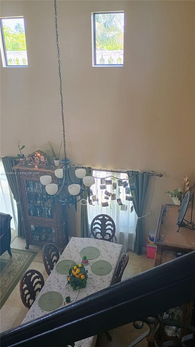 Double-height ceiling featuring high-reaching windows and a multi-arm chandelier