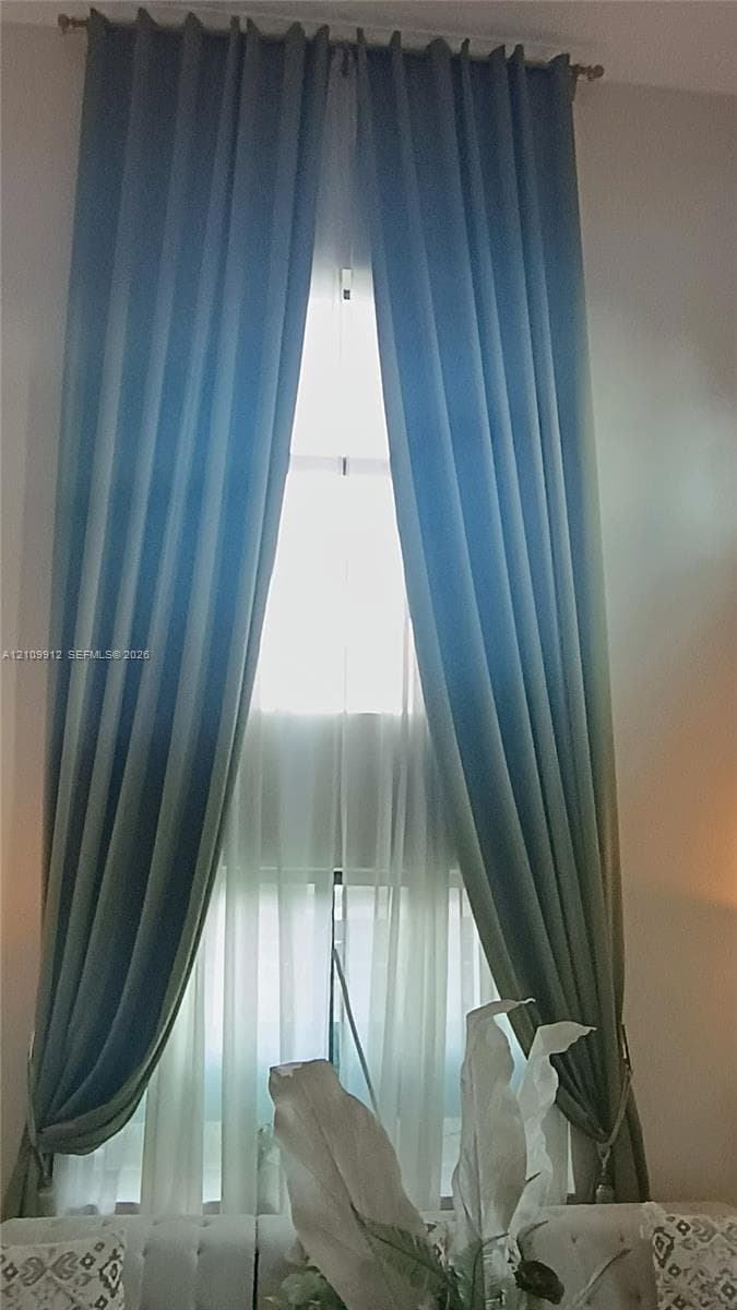 Floor-to-ceiling window featuring a metal curtain rod and hardware