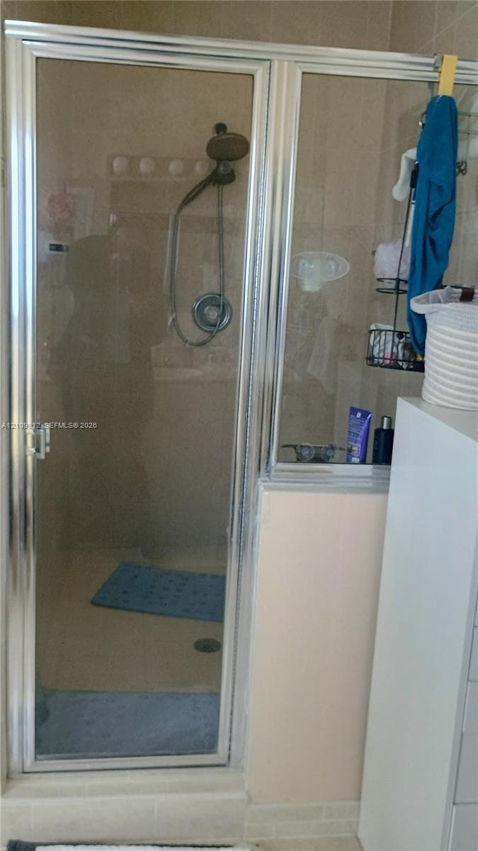 Shower enclosure featuring a chrome-framed glass door, wall-mounted showerhead, and tile surround