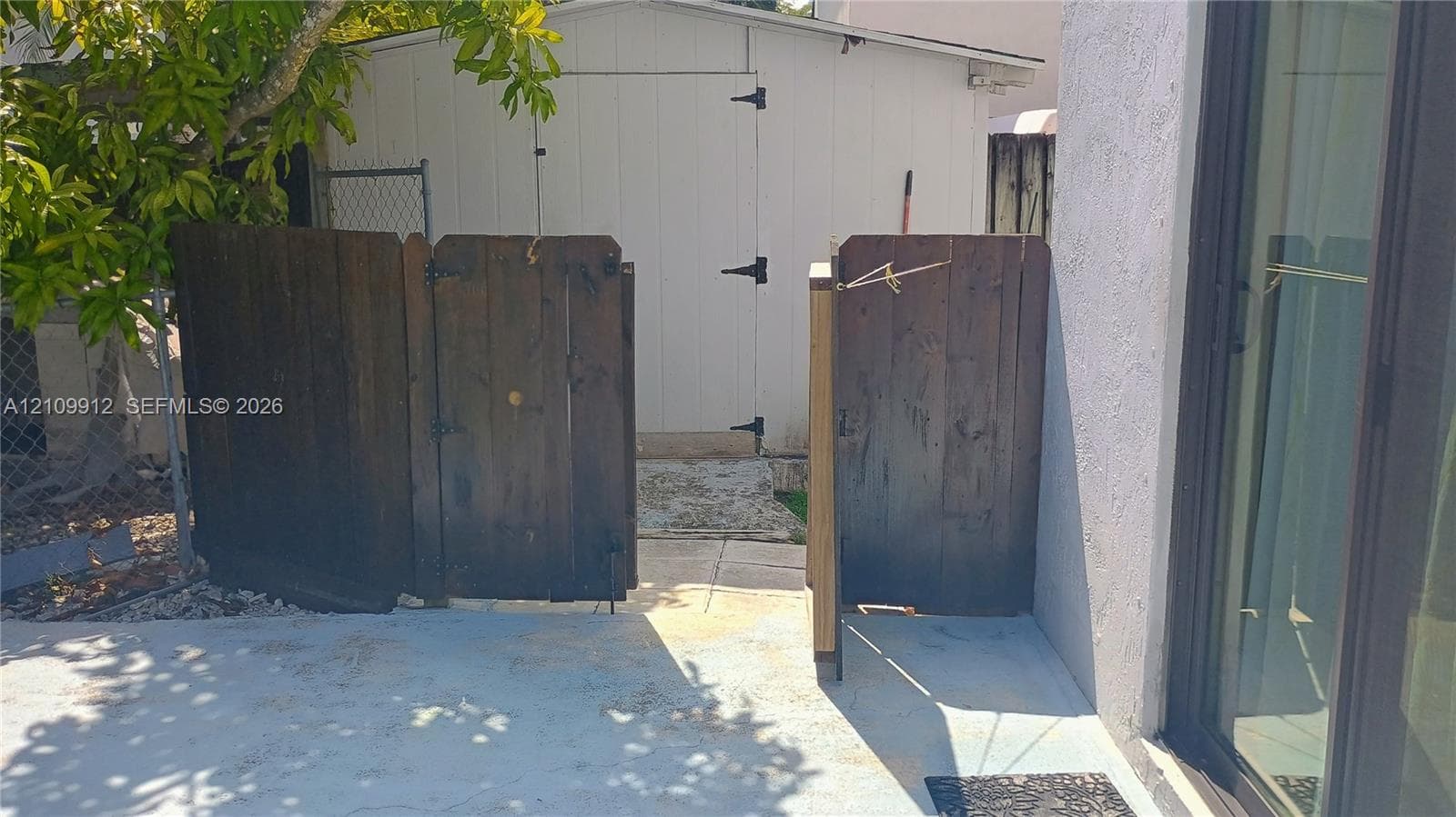 Exterior area featuring a concrete patio, wood-paneled privacy gate, and a detached storage shed