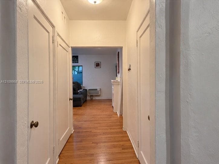 Hallway featuring wood-finish flooring, white paneled doors, and a neutral wall finish