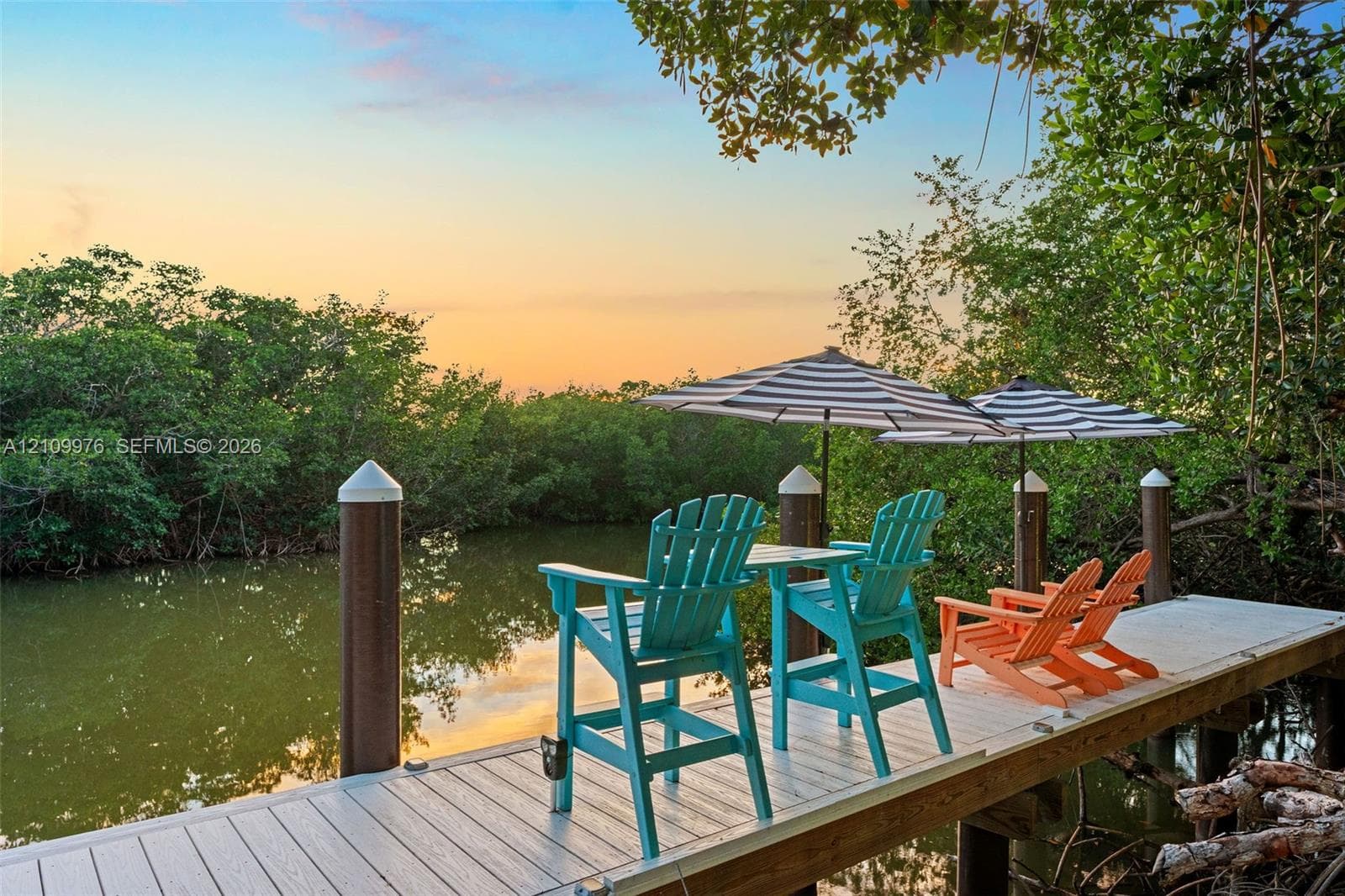 Waterfront dock featuring composite decking and anchored pilings surrounded by dense mature vegetation