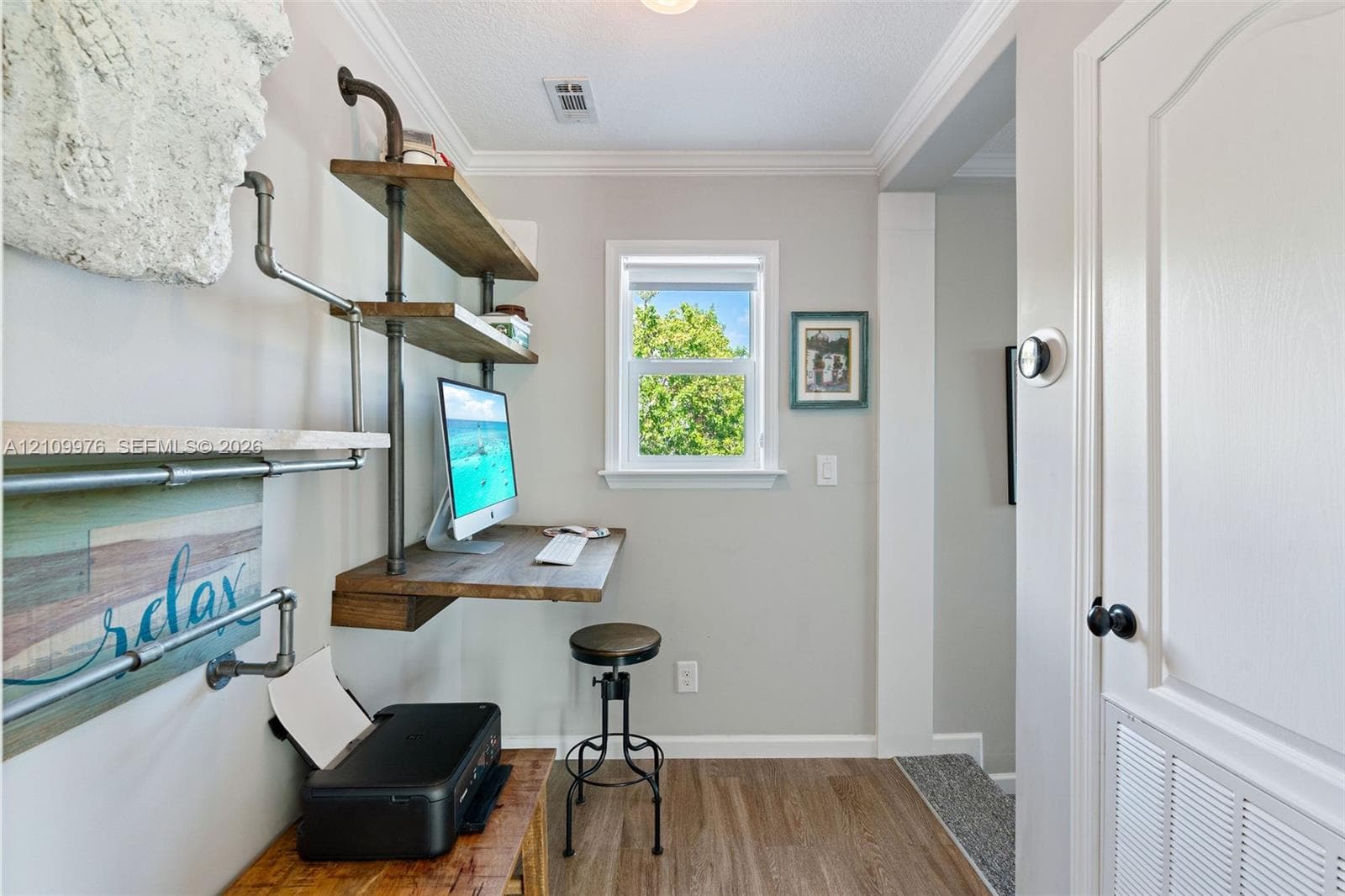 Built-in industrial-style shelving with wood-finish surfaces, wall-mounted desk, crown molding, and wood-finish flooring