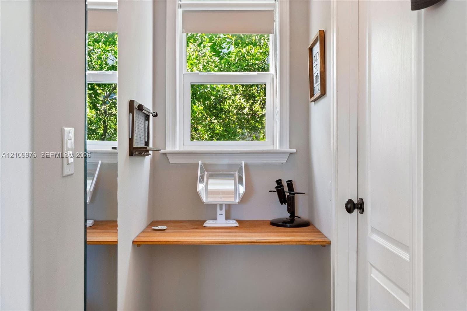 Built-in wooden wall-mounted desk, dual-pane window with white trim, and interior panel door with black hardware