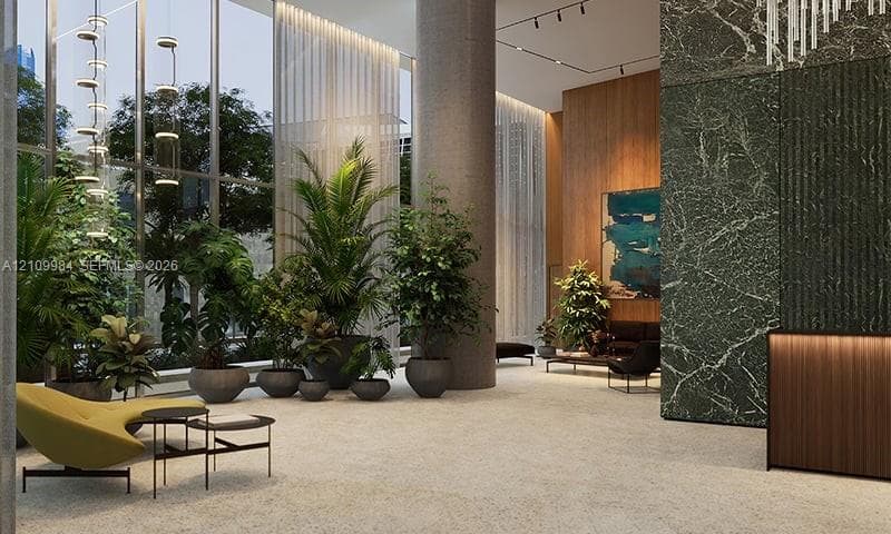 Floor-to-ceiling glass windows, stone-finish flooring, full-height decorative stone wall, wood-finish reception desk, and architectural track lighting