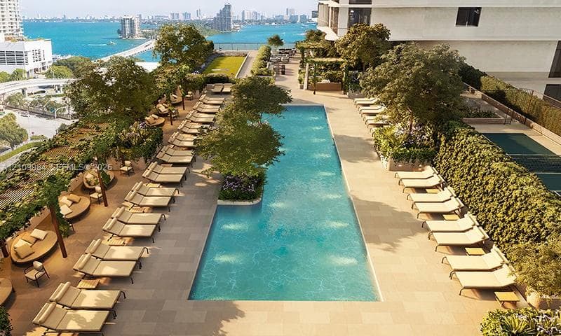 Rooftop terrace featuring an expansive swimming pool, landscaped garden areas, stone-paver decking, shaded pergolas, and water-front scenery