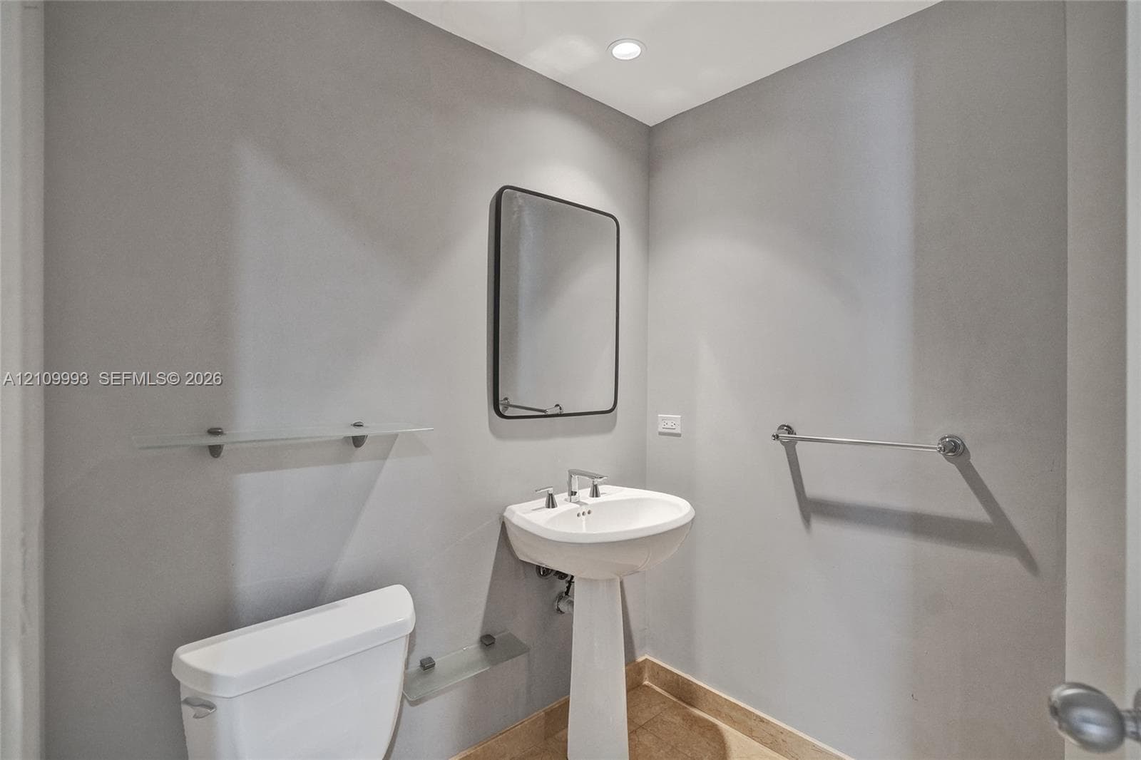 Pedestal sink with chrome faucet, framed rectangular mirror, recessed lighting, and wall-mounted glass shelving