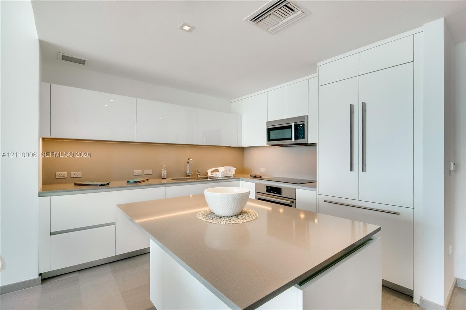 Sleek kitchen featuring flat-panel cabinetry, a central island with quartz countertops, integrated stainless steel appliances, and recessed lighting