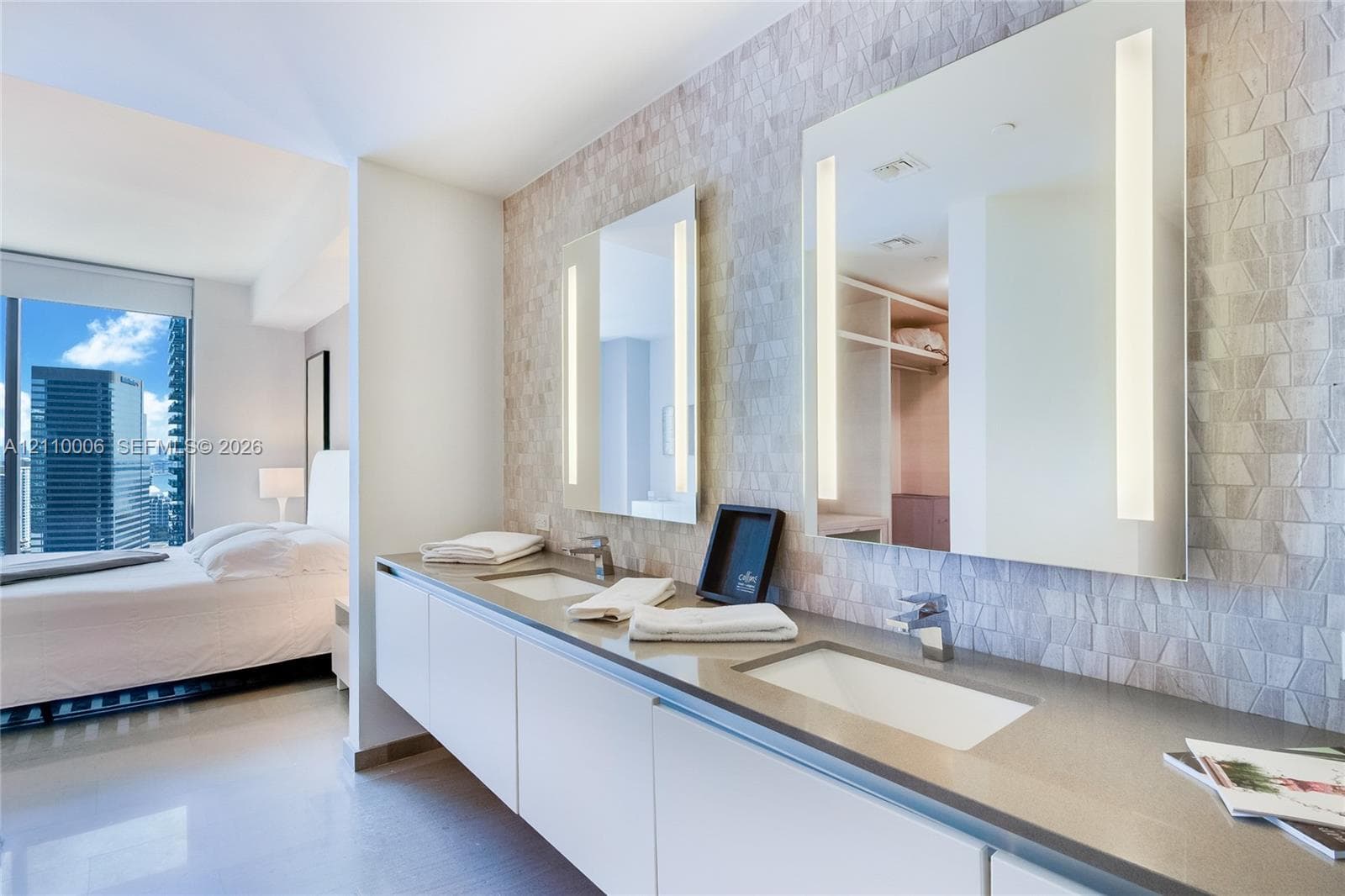 Floating dual-sink vanity with a solid surface countertop, textured tile accent wall, and frameless integrated LED mirrors