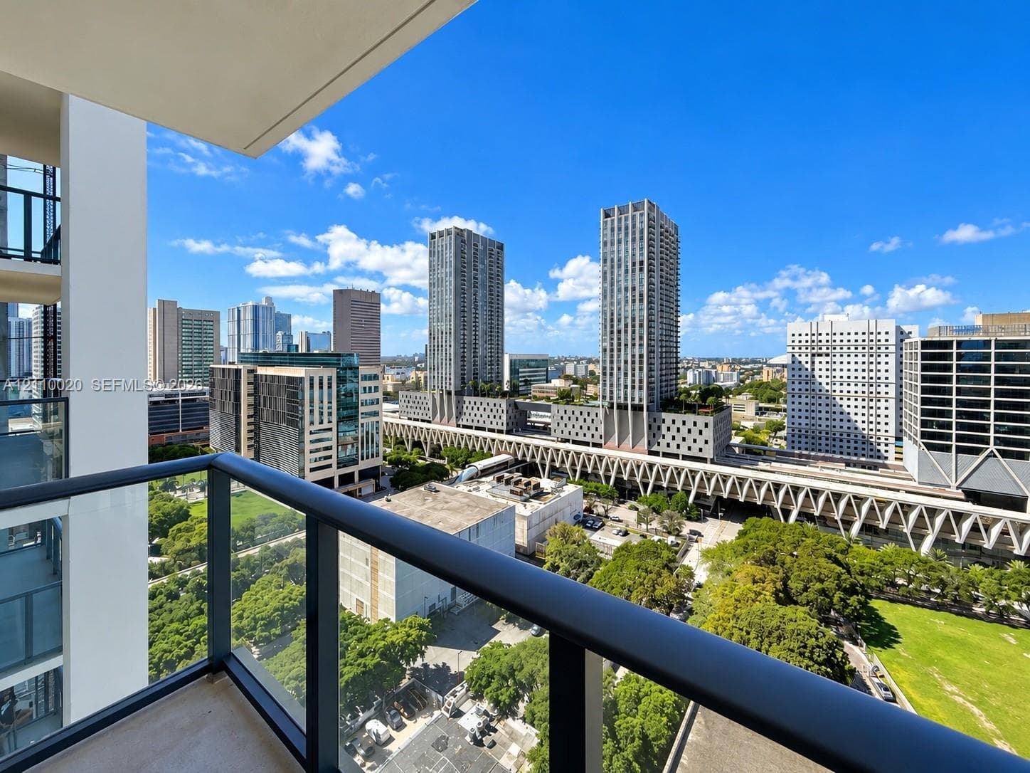 Private balcony featuring a dark metal railing and glass panel inserts, providing an elevated urban landscape perspective